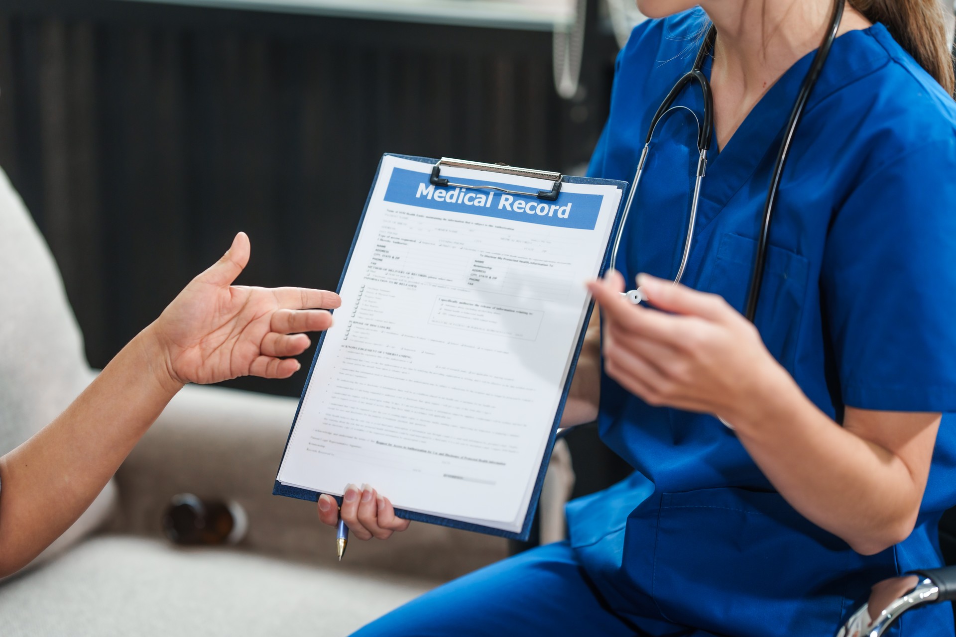 Caucasian female doctor delivers the results of a health check to an elderly Asian patient while they are both seated on the sofa.